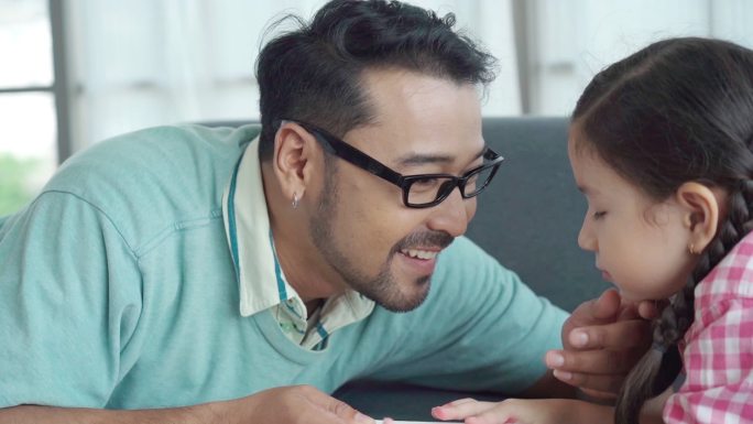 亚洲单身父亲在家照顾女儿，玩耍、教学、女孩制作父亲节问候演员、家庭教育理念、玩面对面游戏和偷窥游戏