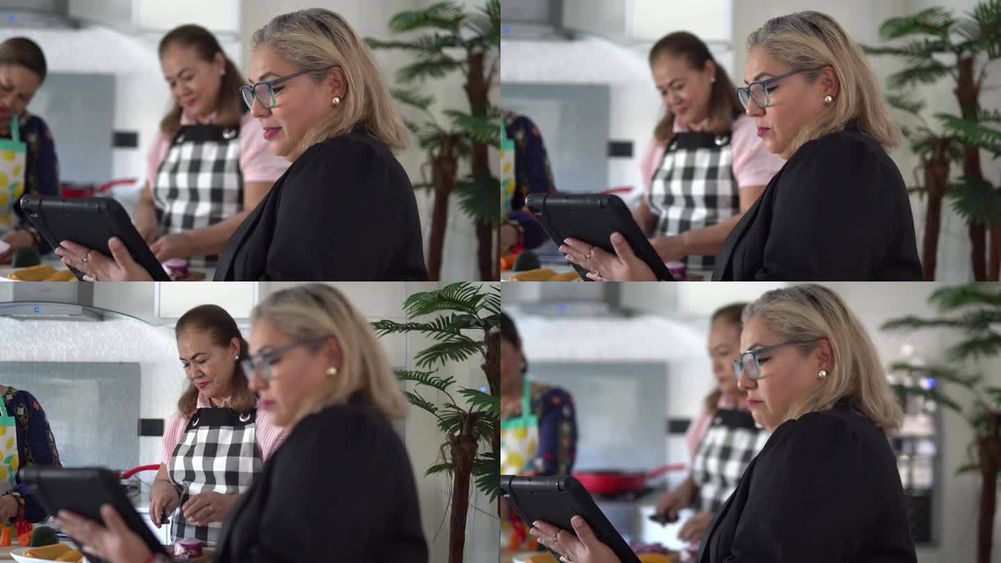 女性拉丁朋友在家里切菜和使用数字平板电脑-准备墨西哥塔梅尔美食