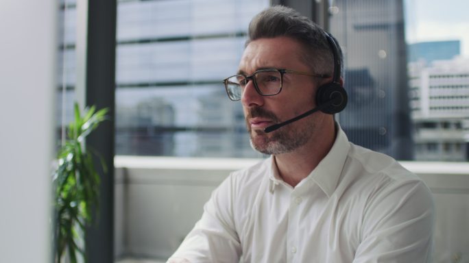 一位成熟商人在现代办公室使用耳机和电脑的4k视频片段