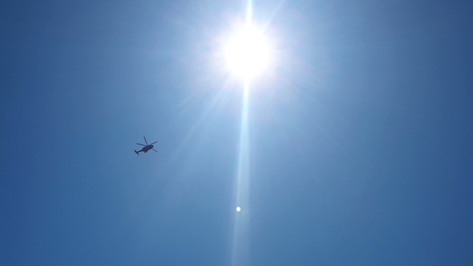 直升飞机掠过太阳和天空