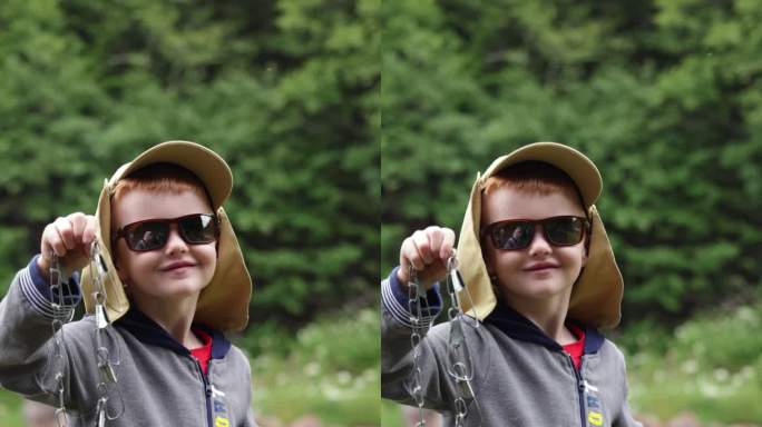 可爱的红发男孩在魁北克的河里钓鱼，并展示了他当天捕获的一条鳟鱼
