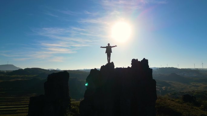 男人登山成功站在山顶挥手庆祝举手欢呼双臂