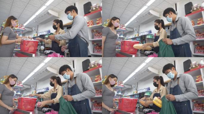 杂货店工作人员为顾客结账。柜台上的亚洲女人在超市买杂货。顾客使用袋子，通过扫描二维码和信用卡进行回收