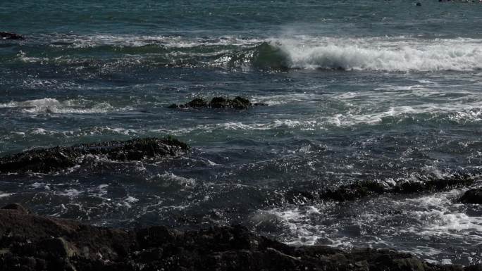 逆光下的大海礁石海浪浪花渔船养殖浮漂