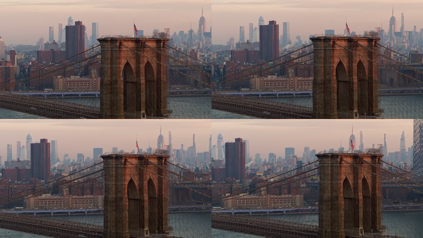 布鲁克林大桥上的清晨车流，塔顶挂着美国国旗，背景是曼哈顿天际线的远景，空中视角模糊了。无人机空中视频