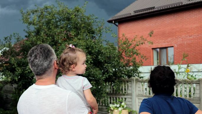父母带着女儿看着暴风云。