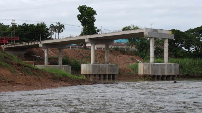 河流在运河上流向未完工混凝土桥墩下方的低角度视图。