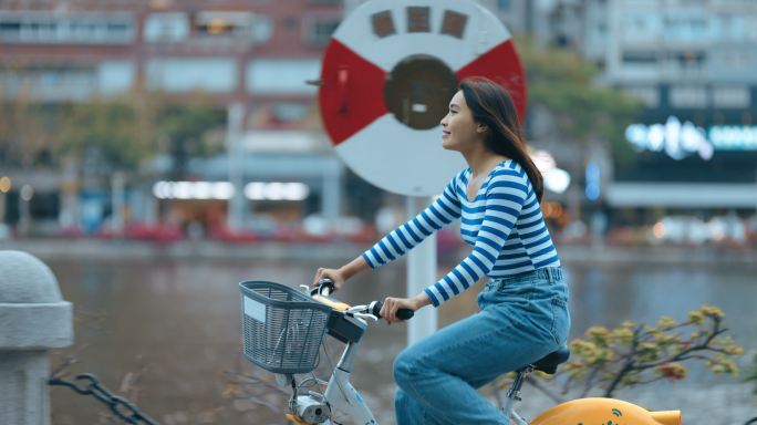 美丽的女孩租自行车穿过城市