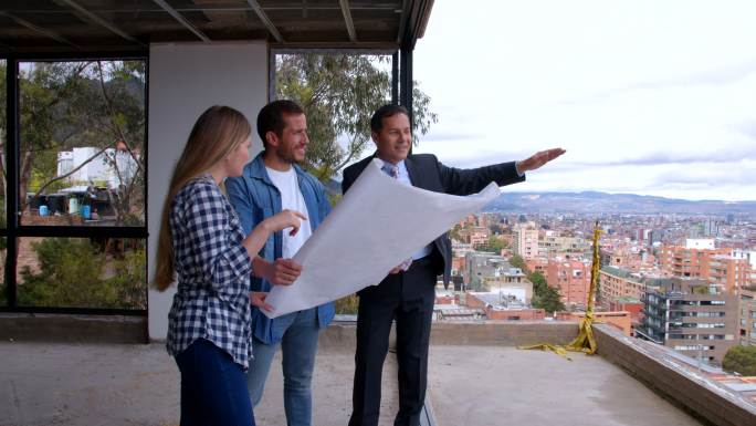 建筑承包商向这对幸福的夫妇展示蓝图，并解释他们新家施工现场的周围环境