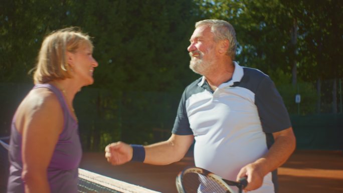 SLO MO在阳光明媚的一天，老年男女在网球比赛后拥抱、谈笑