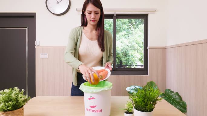 刮烂蔬菜的女人扔掉烂菜浪费食物屋子塑料袋