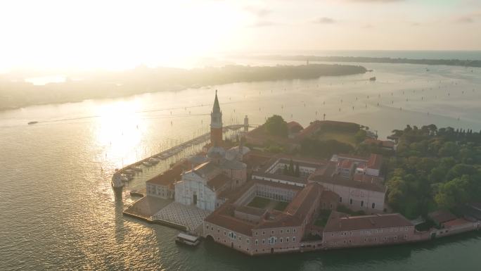 威尼斯群岛圣乔治马焦雷教堂的空中无人机日出场景和船在圣马可广场对面的泻湖碧水之间的交通，威尼斯同名岛
