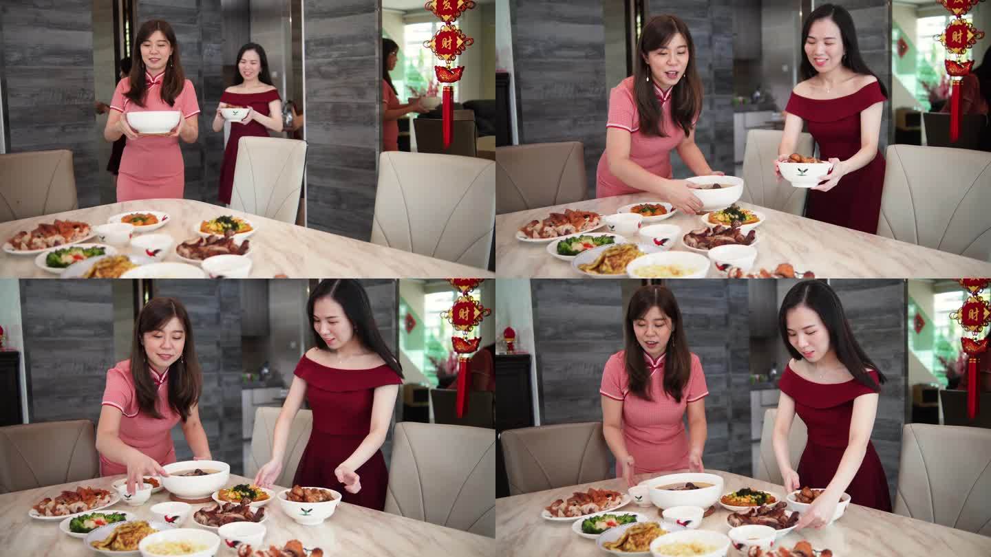两个亚裔中国妹妹在中国新年期间从厨房里拿食物放在餐桌上