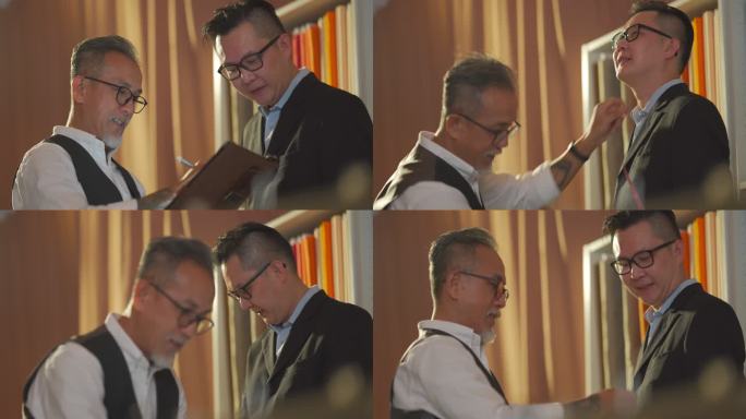 亚洲华裔高级男子裁缝用卷尺测量客户的体型，以便在工作室制作新西装，并用数字平板电脑记录下记录数字