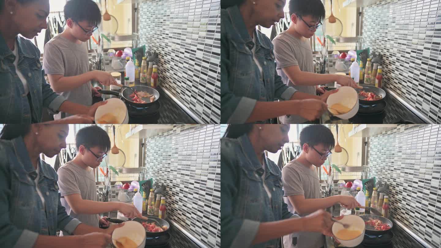 亚裔中国少年男孩在厨房做饭，他的养母在厨房