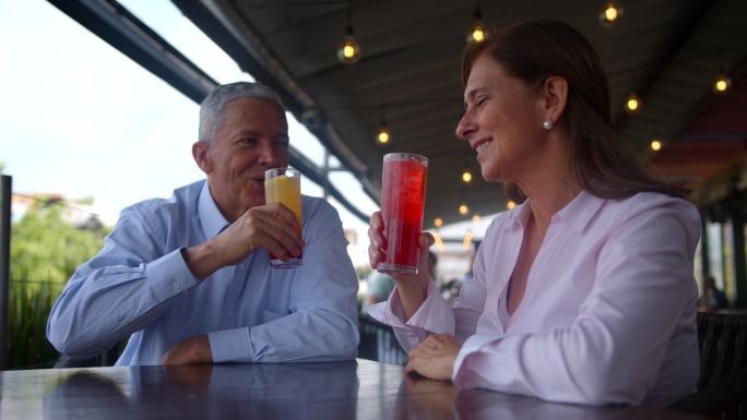 一对美丽的高级夫妇在餐厅约会，一边喝鸡尾酒一边微笑着敬酒