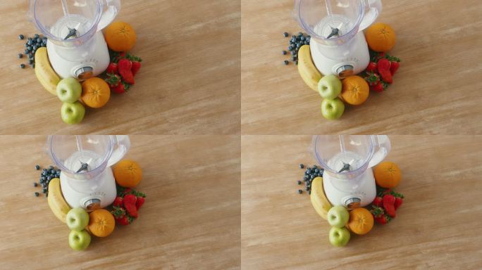 新鲜草莓、香蕉、青苹果、浆果和橙子的俯视图，以及用于制作健康奶昔的搅拌机。