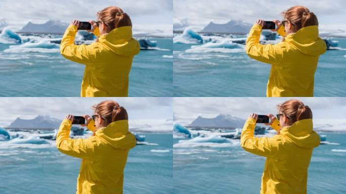 女游客用智能手机拍摄冰岛冰川泻湖和水鸟飞过冰面的照片