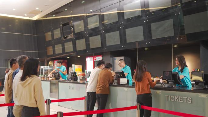后视图亚裔华人在电影院排队购买电影票和快餐