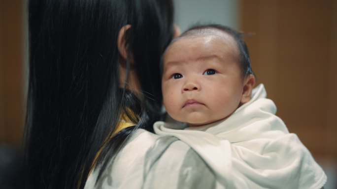 美丽的亚洲母亲在客厅里抱着新生儿