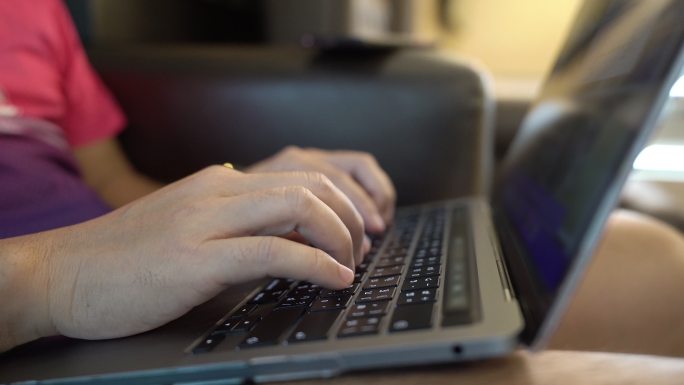 男人在笔记本电脑上工作，在笔记本电脑键盘上打字。