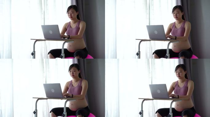 亚洲孕妇在家工作时坐在健身球上