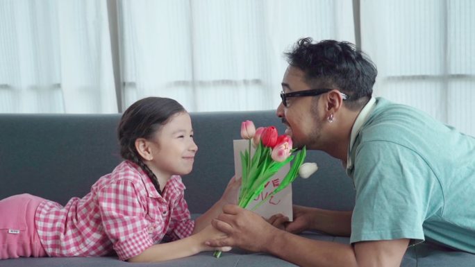 亚洲单亲父亲在家照顾女儿，玩耍、教学，女孩制作父亲节贺词，家庭教育理念，女孩给父亲送郁金香花