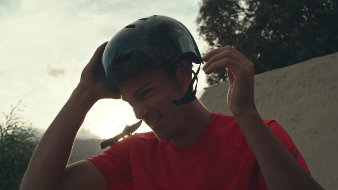 一位年轻帅气、自信、快乐的白人男子BMX车手在出发前戴上头盔微笑，开始练习，为即将到来的自行车越野赛