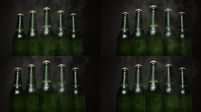 五个绿色啤酒瓶一个接一个地站在黑色背景上