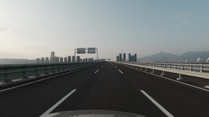 从一辆正在行驶的汽车上向外看，进入河对桥的道路