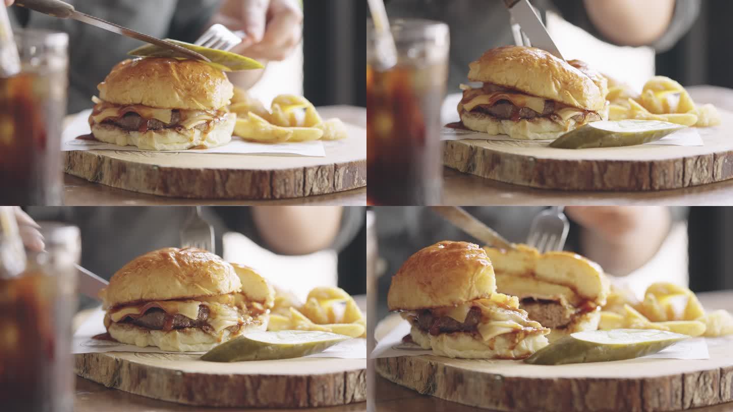 人类用叉子和餐桌刀切汉堡的特写镜头。