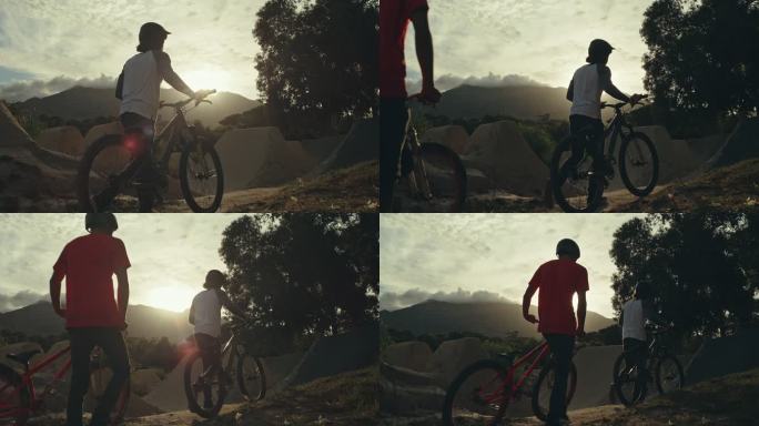 两名年轻的男性BMX自行车骑手，一边步行，一边将自行车推到泥土跑道上的坡道上，一边练习，为即将到来的