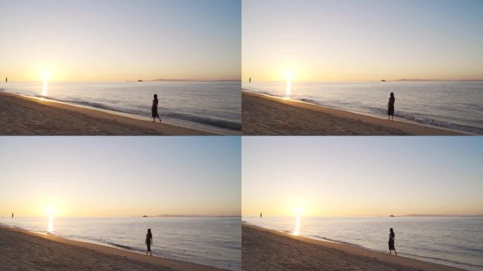 日出阳光下美女走在海边海滩沙滩漫步背影女