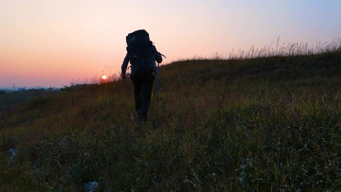 登山运动员背着登山包成功登顶攀登顶峰意境