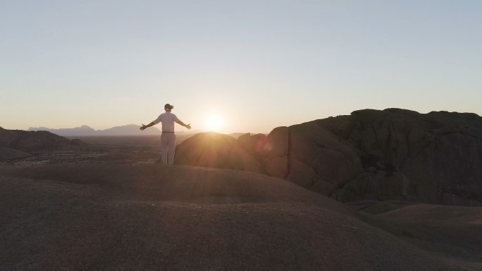 男人在山峰上张开双臂。戴着虚拟现实眼镜。鸟瞰图