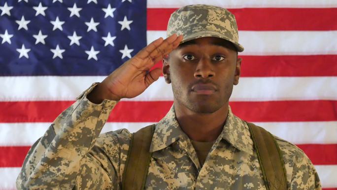 骄傲的美国士兵站在美国国旗前敬礼