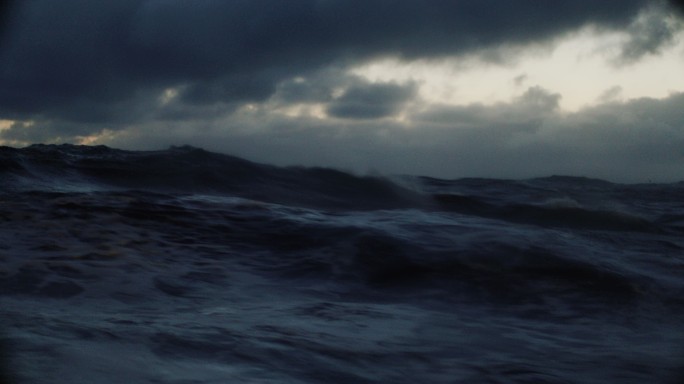 夜晚，从蓝色波涛汹涌的海面上的一艘船上：海浪暗淡的海景