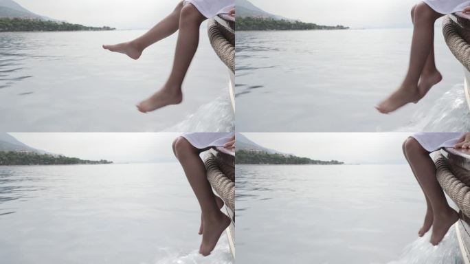 孩子的双腿在游艇的边缘晃动，同时在海上移动。