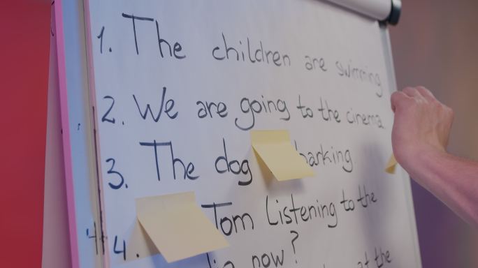 一位年轻的英语老师用白板上的贴纸为他的在线学生准备考试，以隐藏正确答案