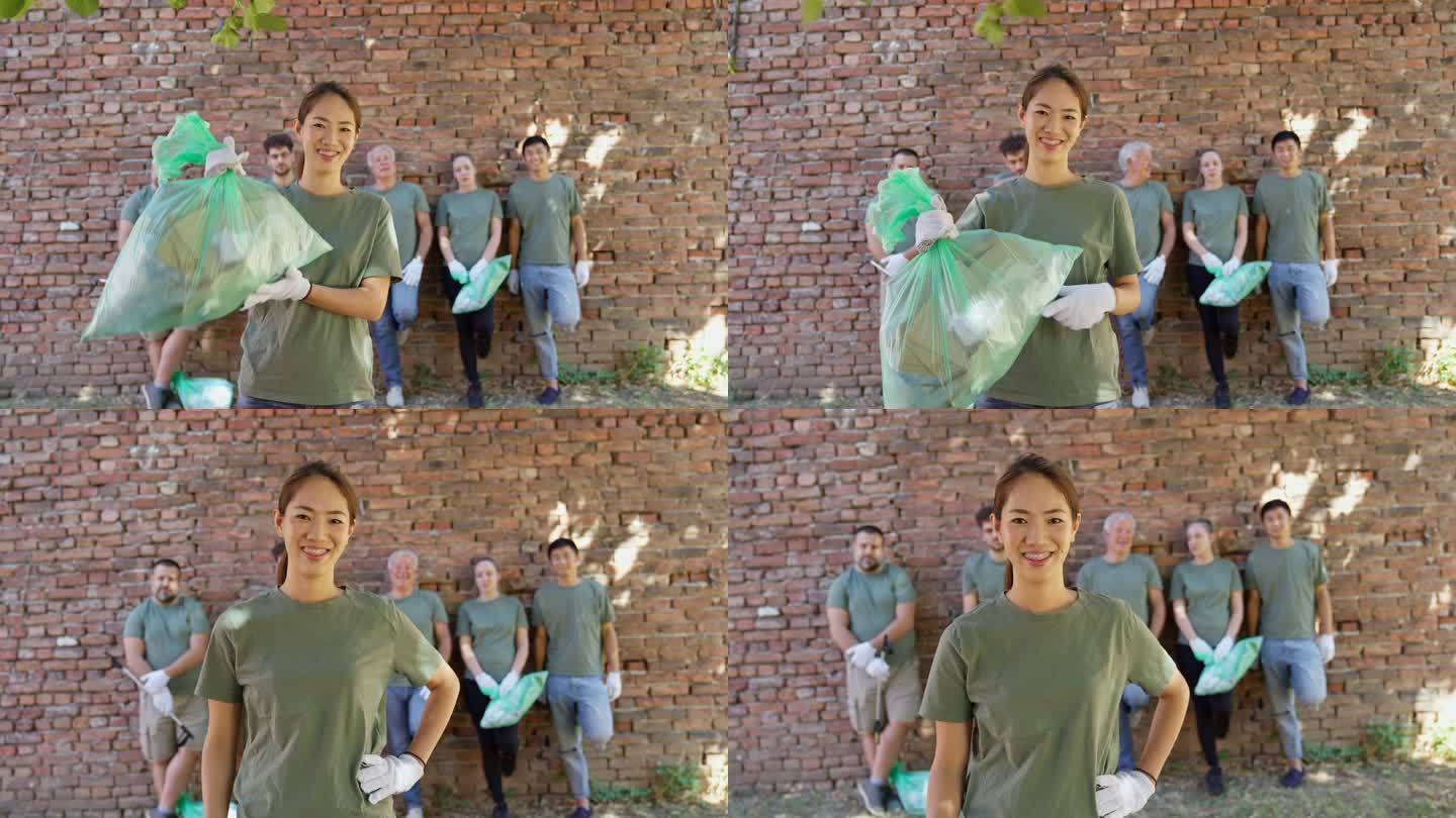 环境清理后，志愿者在志愿者队伍前拿着垃圾袋的肖像