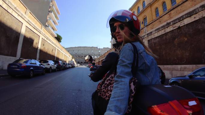 自拍滑板车骑行：在罗马竞技场骑摩托车的游客夫妇