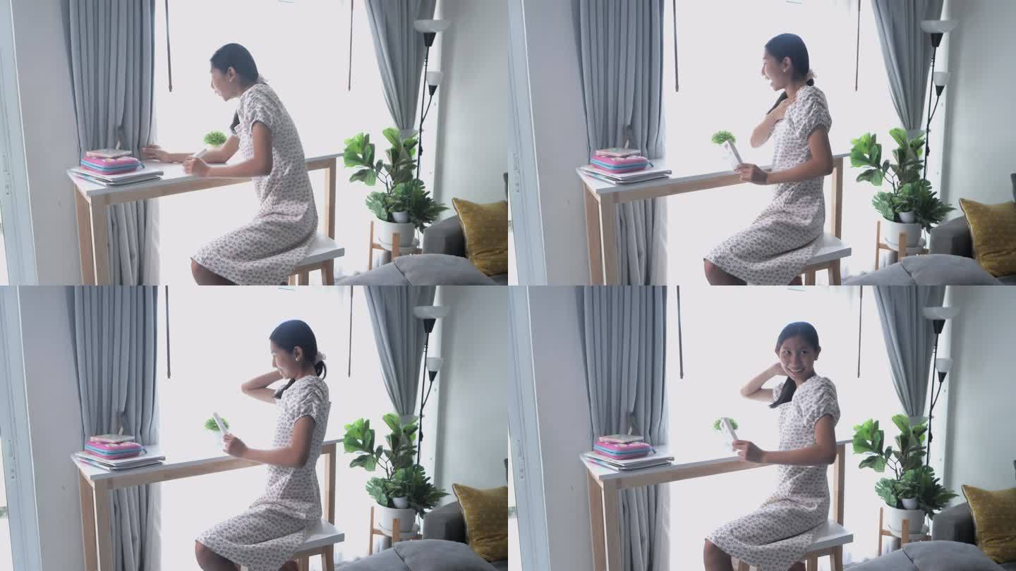 一名亚洲女孩在家里用智能手机制作新冠肺炎快速检测视频，然后在网上课堂上发送给她的老师，健康的生活方式