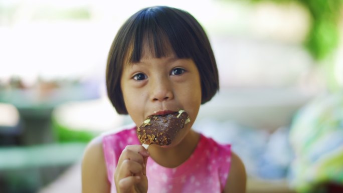 可爱的女孩正以积极的情绪吃巧克力冰淇淋零食，放松心情，享受美食。