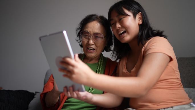祖母和孙女在家里的数字平板电脑上视频通话