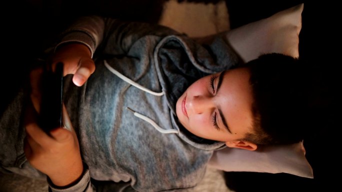 青少年与躺在沙发上的智能手机上的朋友聊天，社交网络