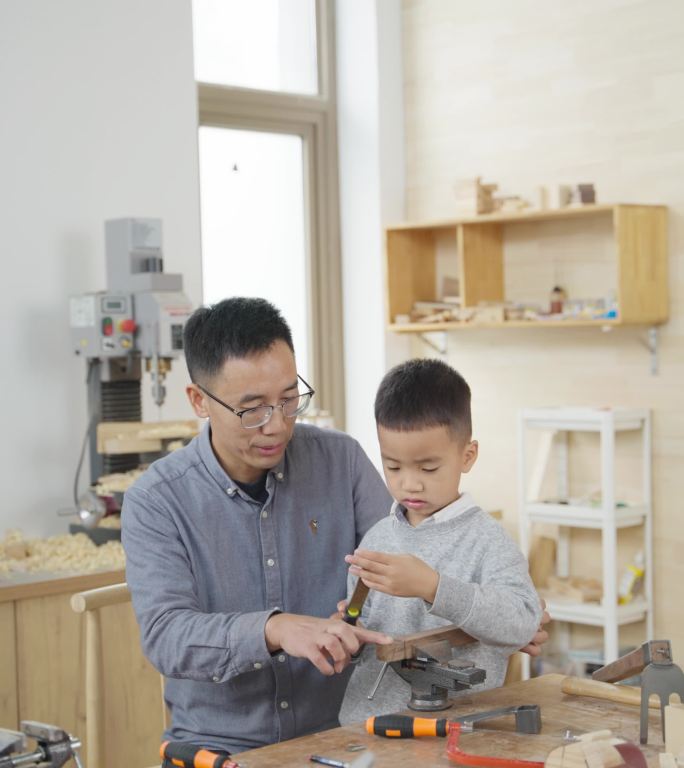 父亲指导小男孩做木工DIY动手能力培养