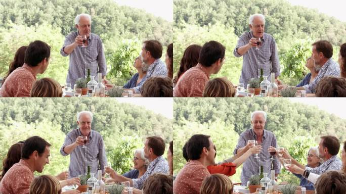 快乐的老人在餐桌上向家人举杯