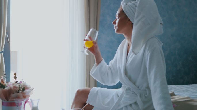 一名女子在酒店房间吃早餐时喝橙汁
