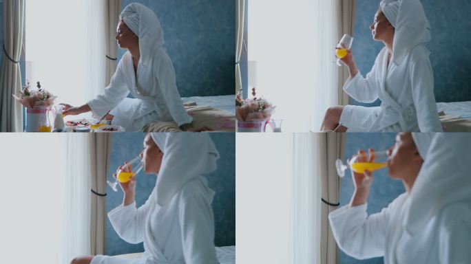 一名女子在酒店房间吃早餐时喝橙汁