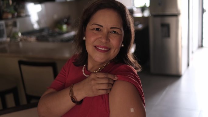 一位快乐的成熟拉丁女性在接种疫苗后展示手臂的肖像